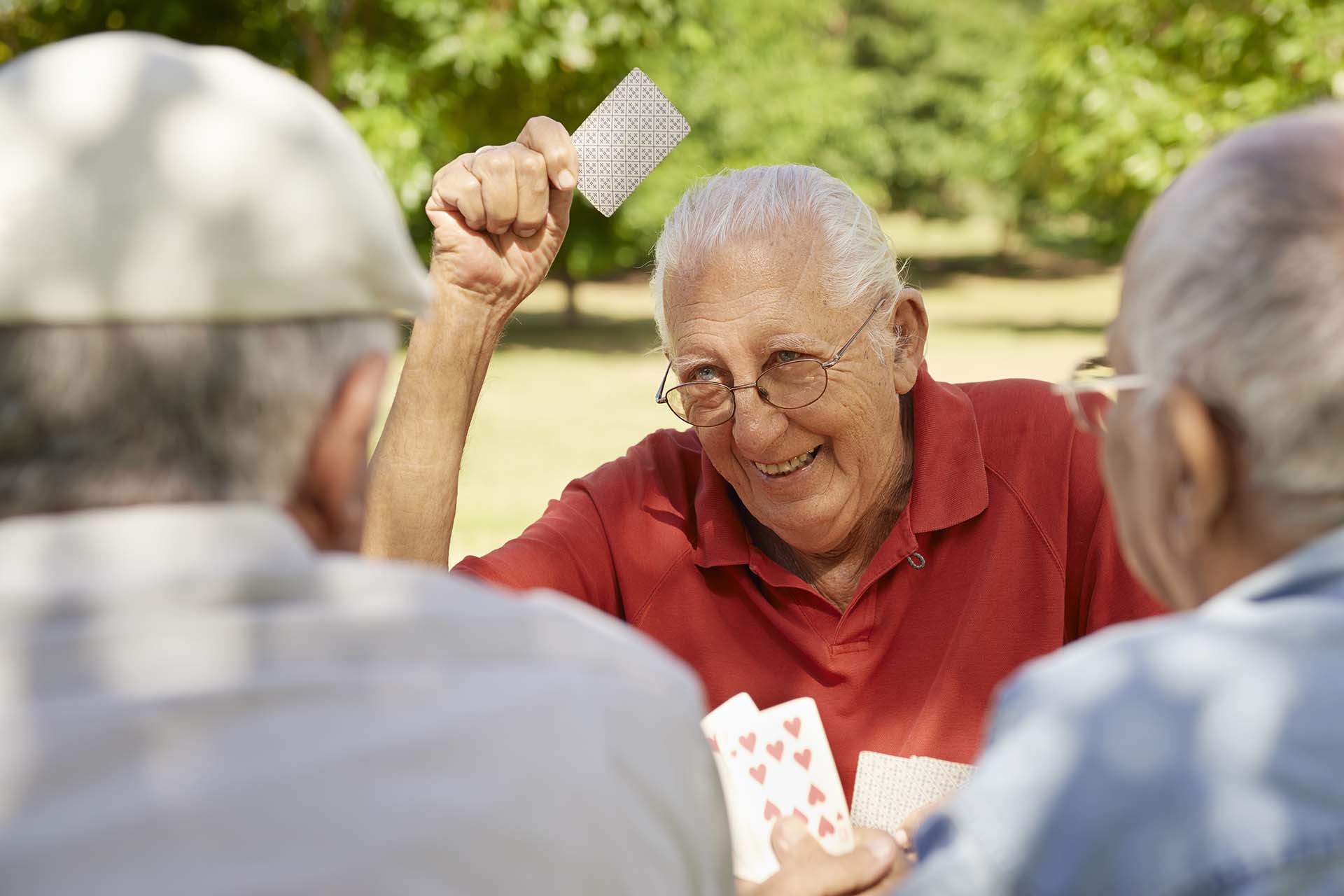 Active retirement, old people and seniors free time, group of three elderly men having fun and playing cards game at park